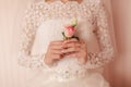 The bride holding in hand close-up the groom`s buttonhole flowers with white roses, and green and greenery Royalty Free Stock Photo