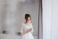 The bride holding in hand close-up the groom`s buttonhole flowers with white roses, and green and greenery. Bride`s Preparations