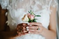 The bride holding in hand close-up the groom buttonhole flowers with white roses, and green and greenery. Bride`s Preparations