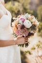Bride holding in hands small wedding bouquet in orange autumn colors Royalty Free Stock Photo