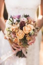 Bride holding in hands small wedding bouquet in orange autumn colors Royalty Free Stock Photo