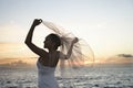 Bride holding veil on beach