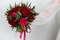 The bride holds a beautiful bouquet of red roses and peonies at arm's length. Royalty Free Stock Photo