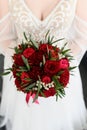 The bride holds a beautiful bouquet of red roses and peonies in her hand. Royalty Free Stock Photo