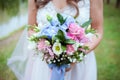 The bride holds a beautiful pink blue and green wedding flowers bouquet in her hands on green background. Royalty Free Stock Photo