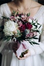 The bride holds a beautiful wedding bouquet of white chrysanthemums and purple roses Royalty Free Stock Photo