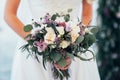 The bride holds a bouquet in her hands near the wedding arch