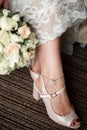 The bride holds a bouquet near her feet in shoes Royalty Free Stock Photo