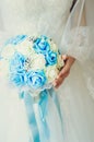 The bride holds a bouquet of roses. Fragment of a white wedding dress