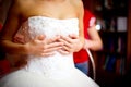 Bride holds dress on herself while bridesmaids lace her corset Royalty Free Stock Photo