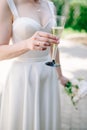 The bride holds a glass of delicious champagne