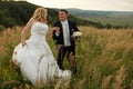 Bride holds groom's hand walking around the field Royalty Free Stock Photo