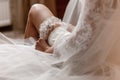 The bride holds in hand lose-up garter in hotel room. morning preparation wedding concept Royalty Free Stock Photo