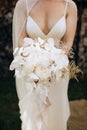 The bride holds in her hands a beautiful wedding bouquet of white orchids and peonies Royalty Free Stock Photo