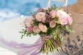 The bride holds a pink and lilac wedding bouquet in her arms against the background of the sea Royalty Free Stock Photo