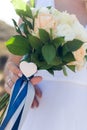 The bride holds a wedding bouquet of white and beige roses