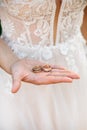 Bride holds wedding rings on her hand against the background of a white lace wedding dress.body parts, hold hands Royalty Free Stock Photo