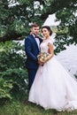 Bride hugging groom on the river bank under a tree