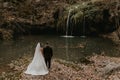 bride hugs groom near small pond lake river waterfall Burbun Royalty Free Stock Photo