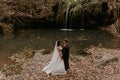 bride hugs groom near small pond lake river waterfall Burbun Royalty Free Stock Photo