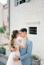 Bride kisses groom on the cheek near the white facade of an ancient building Royalty Free Stock Photo