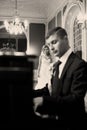 Bride kisses groom's cheek while he plays on the piano Royalty Free Stock Photo