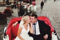 Bride kisses groom tenderly sitting in a red carriage Royalty Free Stock Photo