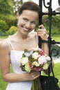 Bride Leaning On Garden Gate Holding Bouquet Royalty Free Stock Photo
