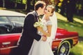 Bride leans on a groom standing on a doorstep of an vintage car Royalty Free Stock Photo