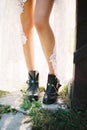 Bride legs in black boots peep out from the slit of a white wicker dress. Close-up