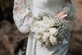 The bride in a long tight white wedding dress holds a beautiful bouquet of white roses Royalty Free Stock Photo