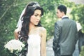 Bride looking back while holding a bouquet with her groom at beh Royalty Free Stock Photo