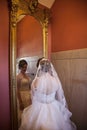 Bride looking at herself in large gold mirror