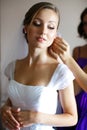 Bride looks funny while bridesmaid adjusts an earring Royalty Free Stock Photo