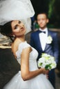 Bride looks over her shoulder and smiles while groom waits on th