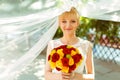 Bride looks shy holding a bouquet of yellow and red roses Royalty Free Stock Photo