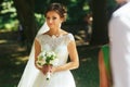 Bride looks thoughtful holding a bouquet in her arms