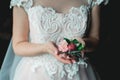 Bride in a luxurious wedding dress holding a wedding buttonhole made of roses Royalty Free Stock Photo