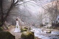 The bride in a luxurious white dress is standing by the river high in the mountains
