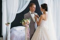 The bride in a luxurious white dress with a veil puts on a boutonniere groom in a gray suit. Wedding couple on wedding