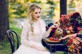 The bride with the owl. Beautiful smiling bride is sitting near the served wedding table with red autumn leaves Royalty Free Stock Photo