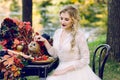 The bride with the owl. Beautiful smiling bride is sitting near the served wedding table with red autumn leaves Royalty Free Stock Photo