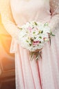 The bride in a pink dress on the wedding day holds a bouquet in her hands. Close-up. Toned photo Royalty Free Stock Photo