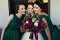 Bride poses with bridesmaids reaching out her hand with bouquet
