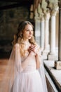 Bride prays with her arms crossed on her chest on a pillared loggia in an old villa on Lake Como. Royalty Free Stock Photo