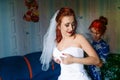 Bride is preparing for the wedding. bridesmaid helps the girl to put on her dress. Royalty Free Stock Photo