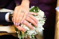 The bride put her hand on her husband`s hand with wedding rings . The newlyweds put their hands on a engagement white bouquet of Royalty Free Stock Photo