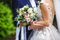 The bride put her hands on the shoulders of the bridegroom. bride with a bouquet of pink and white roses hugs and kiss the groom Royalty Free Stock Photo