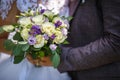 The bride put her hands on the shoulders of the bridegroom. bride with a bouquet of violet and white roses hugs and kiss the groom Royalty Free Stock Photo