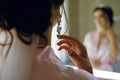 The bride puts on earrings near the mirror, a beautiful curl of brunette, rear view